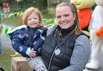 Mother, holding child, mom is wearing Cherrios Challenge medal around her neck