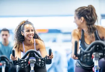 two women riding stationary bikes
