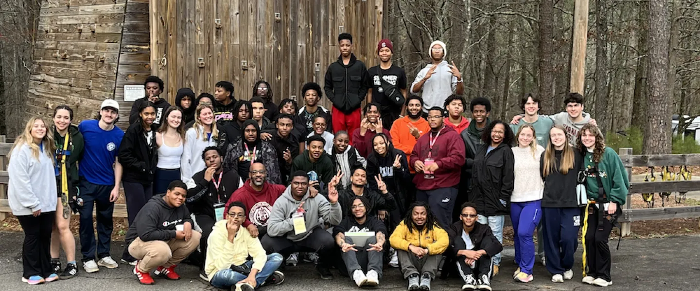 BYMOC group posing for a picture in front of a rock climbing wall