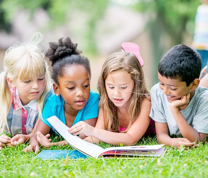 Day Camp kids reading in the grass