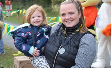 Mother, holding child, mom is wearing Cherrios Challenge medal around her neck