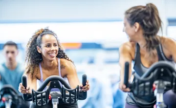 two women riding stationary bikes